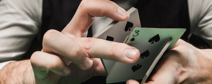 Blackjack Dealer holding a pack of cards with 3 of spades at the bottom